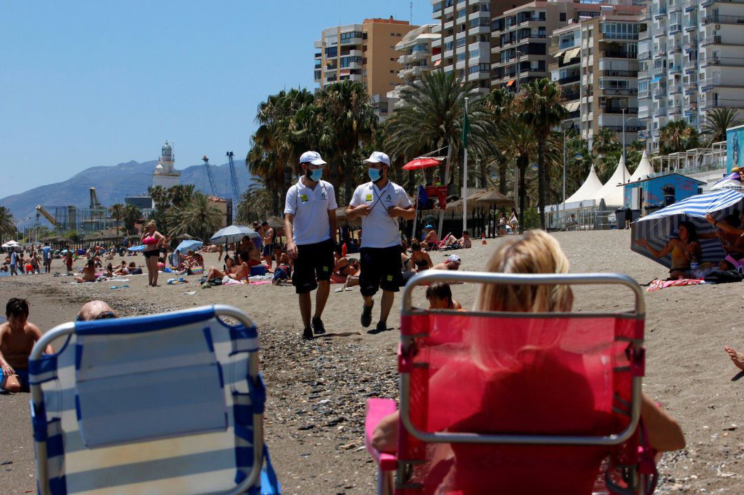 Una pareja de Vigilantes de la playa de Andalucía asesoran a bañistas sobre las medidas preventivas sobre el COVID-19 en la playa de La Malagueta Una pareja de Vigilantes de la playa de Andalucía asesoran a bañistas sobre las medidas preventivas sobre el COVID-19 en la playa de La Malagueta