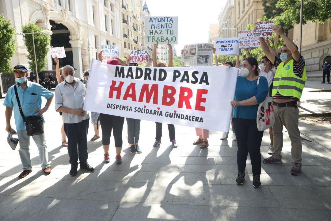 Varias personas sostienen una pancarta donde se puede leer "Madrid pasa hambre" ante el Palacio de Cibeles, sede del Ayuntamiento de Madrid Varias personas sostienen una pancarta donde se puede leer "Madrid pasa hambre" ante el Palacio de Cibeles, sede del Ayuntamiento de Madrid