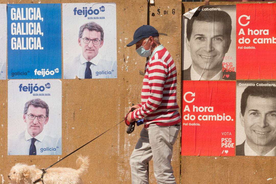 Un hombre pasea su perro en Burela ante carteles electorales. Un hombre pasea su perro en Burela ante carteles electorales.