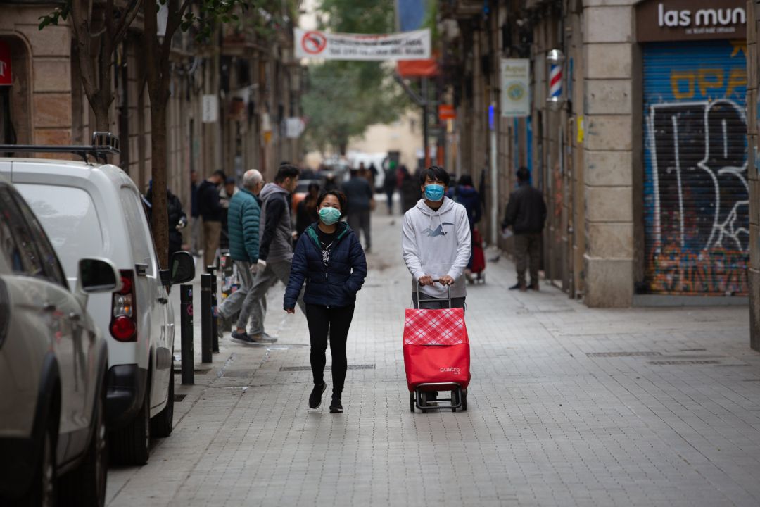 Dos personas protegidas con mascarillas durante el segundo día laborable del estado de alarma por el coronavirus, en Barcelona Dos personas protegidas con mascarillas durante el segundo día laborable del estado de alarma por el coronavirus, en Barcelona