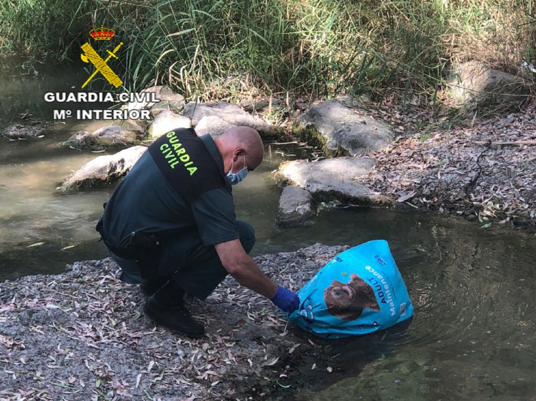 Imagen de un agente examinando una de las bolsas que contenía un perro ahogado Imagen de un agente examinando una de las bolsas que contenía un perro ahogado