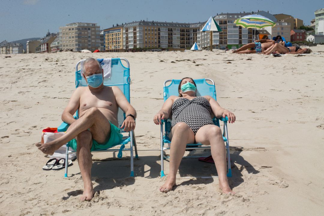 Dos personas protegidas con mascarillas toman el sol en la Playa de A Rapadoira en Foz, en la comarca de A Mariña, Lugo, Galicia (España), a 9 de julio de 2020. El pasado 5 de julio la Xunta ordenó el cierre hasta mañana 10 de julio de los accesos del dis Dos personas protegidas con mascarillas toman el sol en la Playa de A Rapadoira en Foz, en la comarca de A Mariña, Lugo, Galicia (España), a 9 de julio de 2020. El pasado 5 de julio la Xunta ordenó el cierre hasta mañana 10 de julio de los accesos del dis