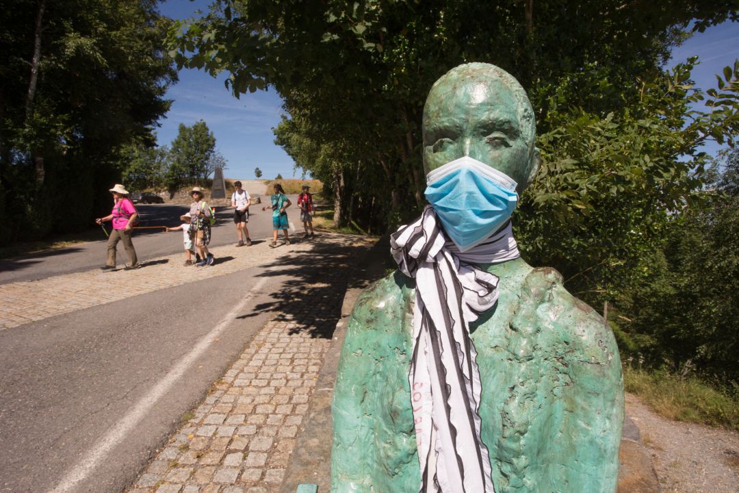 Un grupo de peregrinos llega a O Cebreiro pasando junto a la escultura del coruñés Miguel Couto, que luce desde hace semanas una mascarilla quirúrgica en recuerdo de las víctimas del Covid-19, mientras los peregrinos retornan al Camino francés de la Ruta Jacobea casi un mes después del fin del estado de alarma por el coronavirus, en O Cebreiro, Lugo, Galicia (España), a 15 de julio de 2020 Un grupo de peregrinos llega a O Cebreiro pasando junto a la escultura del coruñés Miguel Couto, que luce desde hace semanas una mascarilla quirúrgica en recuerdo de las víctimas del Covid-19, mientras los peregrinos retornan al Camino francés de la Ruta Jacobea casi un mes después del fin del estado de alarma por el coronavirus, en O Cebreiro, Lugo, Galicia (España), a 15 de julio de 2020
