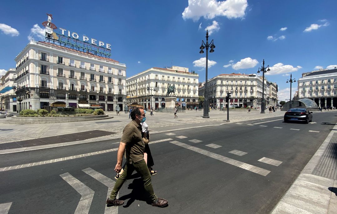 Dos personas cruzan la calle en la Puerta del Sol de Madrid Dos personas cruzan la calle en la Puerta del Sol de Madrid