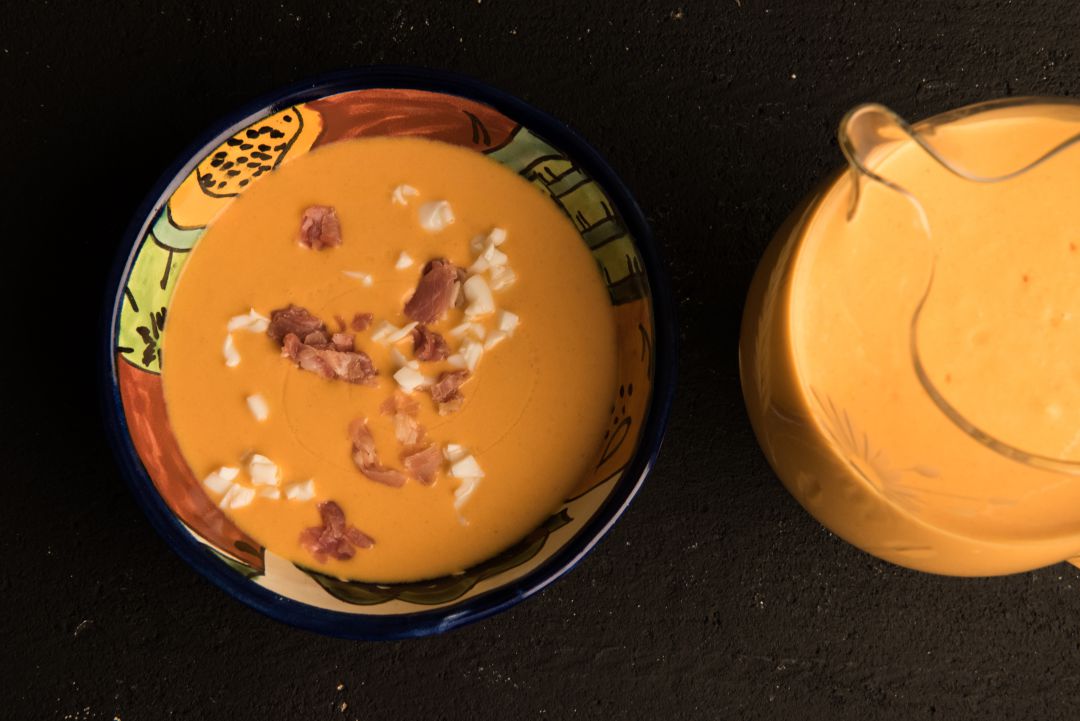 Cuenco con salmorejo con trozos de huevo duro y jamón y jarra con salmorejo Cuenco con salmorejo con trozos de huevo duro y jamón y jarra con salmorejo
