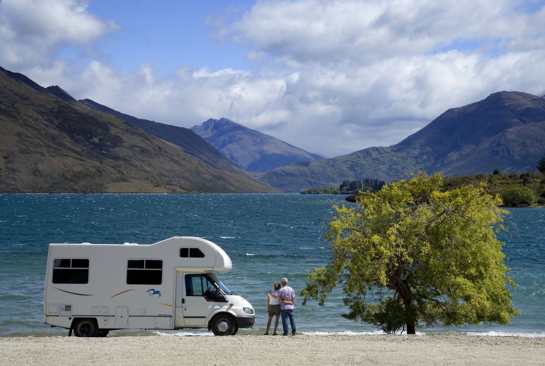 Una pareja contempla el paisaje junto a su autocaravana Una pareja contempla el paisaje junto a su autocaravana