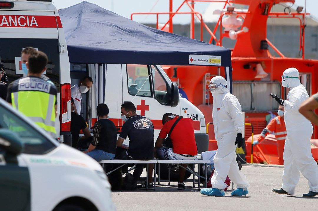 Los sanitarios de la Cruz Roja, enfundados en EPI 's, atienden a varios inmigrantes que han sido interceptados tras alcanzar tierra Los sanitarios de la Cruz Roja, enfundados en EPI 's, atienden a varios inmigrantes que han sido interceptados tras alcanzar tierra