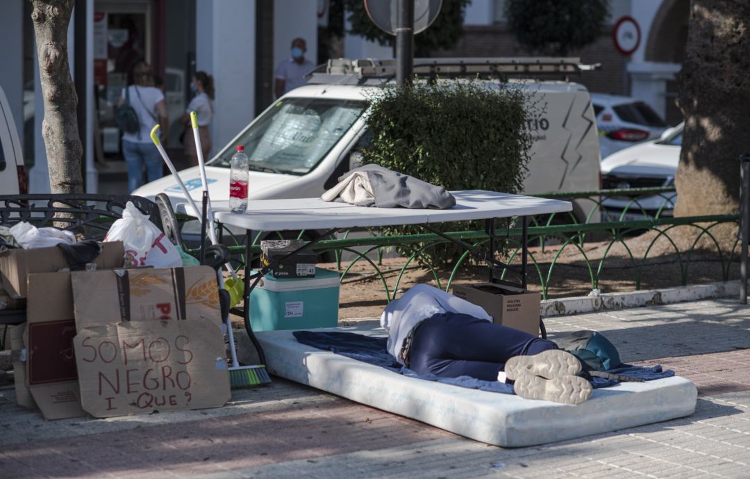 Entre pancartas, un hombre duerme sobre un colchón en plena calle, en la plaza donde se encuentra ubicado el ayuntamiento de Lepe (Huelva), donde en las últimas semanas dos incendios han calcinado los asentamientos precarios en los que vivían decenas de temporeros y temporeras migrantes que piden soluciones a su situación. Entre pancartas, un hombre duerme sobre un colchón en plena calle, en la plaza donde se encuentra ubicado el ayuntamiento de Lepe (Huelva), donde en las últimas semanas dos incendios han calcinado los asentamientos precarios en los que vivían decenas de temporeros y temporeras migrantes que piden soluciones a su situación.