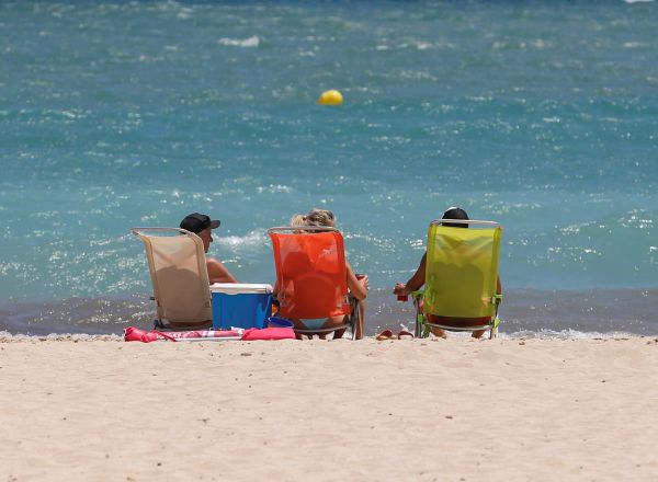Tres personas toman el sol en la orilla de la playa de Magaluf, Palma de Mallorca.