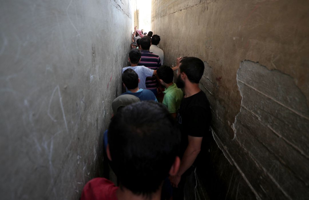 Un grupo de hombres y adolescentes sirios hacen cola en una estrecha calle de la ciudad de Sweida. Un grupo de hombres y adolescentes sirios hacen cola en una estrecha calle de la ciudad de Sweida.