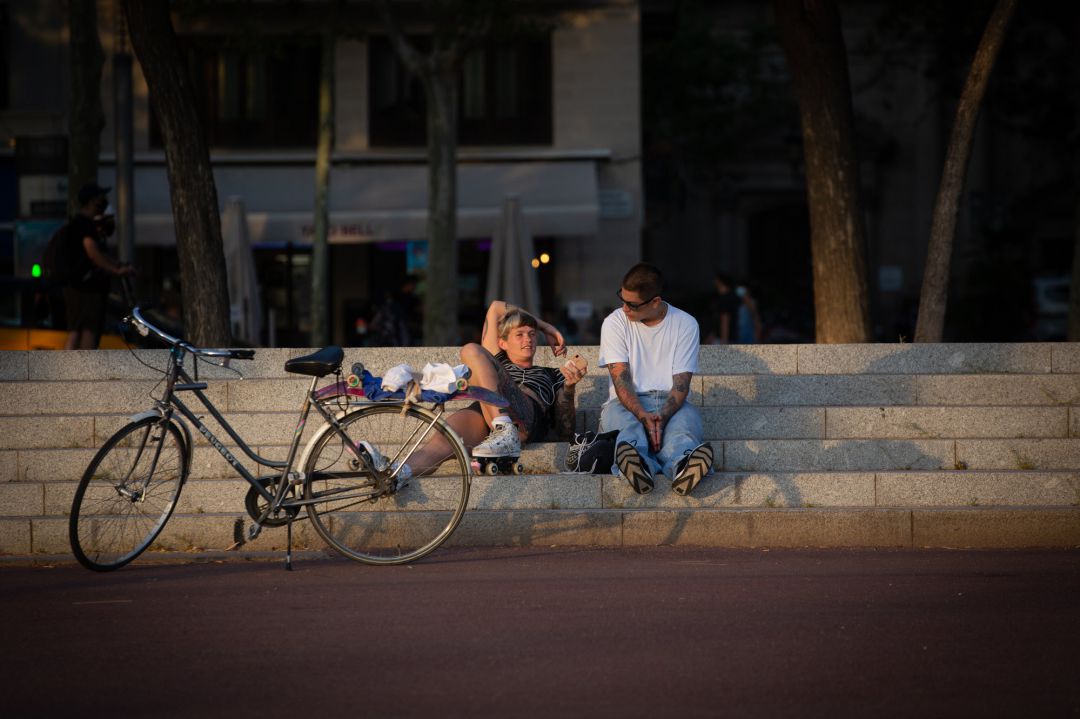 Dos jóvenes descansan junto a una bicicleta en Barcelona. Dos jóvenes descansan junto a una bicicleta en Barcelona.