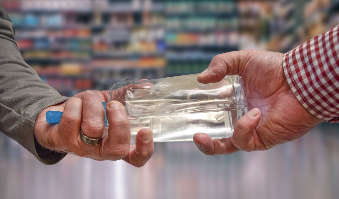 Dos personas sujetan una botella de gel hidroalcohólico Dos personas sujetan una botella de gel hidroalcohólico