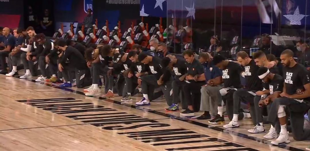 Árbitros, entrenadores y jugadores, arrodillados durante el himno americano Árbitros, entrenadores y jugadores, arrodillados durante el himno americano