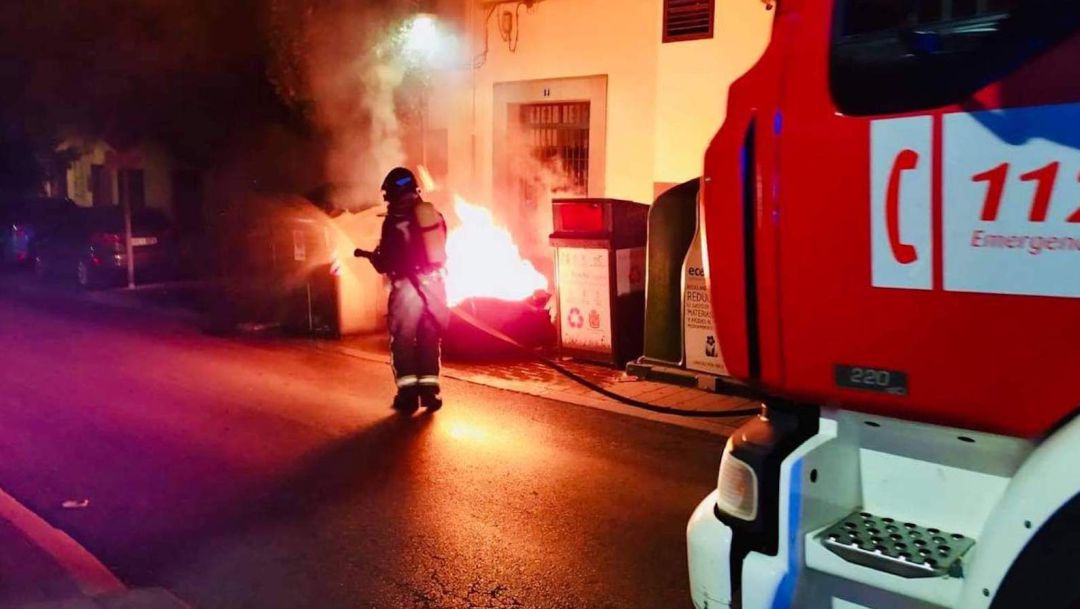 Un bombero apaga uno de los contenedores incendiados. Un bombero apaga uno de los contenedores incendiados.