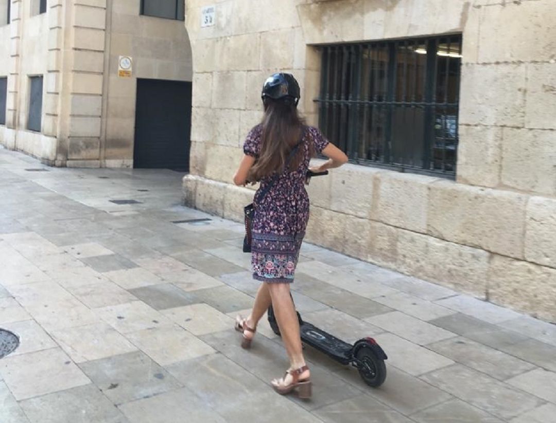 Una usuaria circula correctamente al bajarse del patinete por la acera Una usuaria circula correctamente al bajarse del patinete por la acera