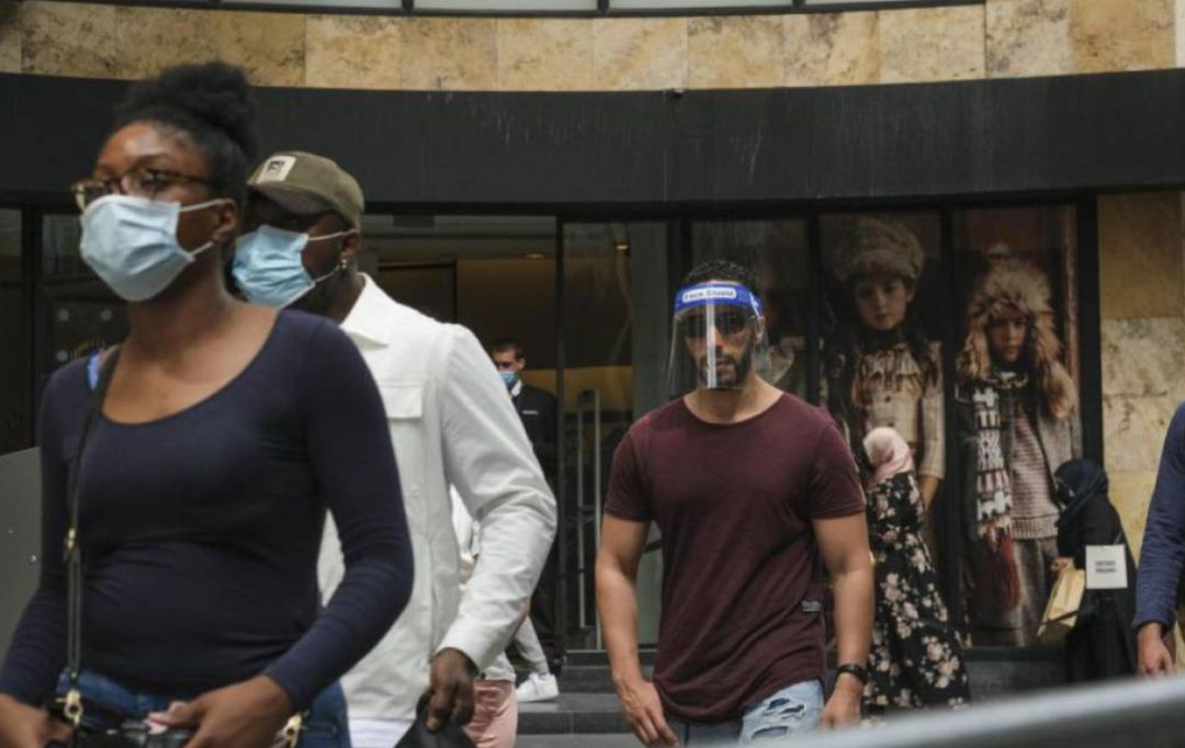 Viandantes pasean por una ciudad con mascarillas y protección facial Viandantes pasean por una ciudad con mascarillas y protección facial