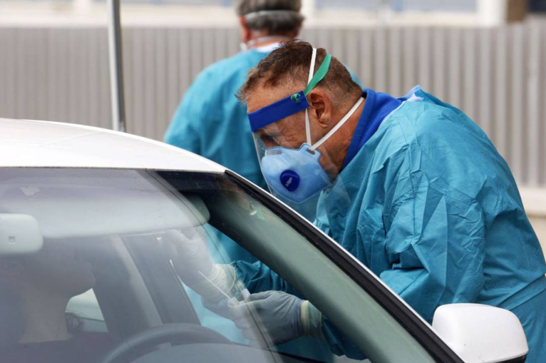 Un sanitario realiza un test PCR a través de la ventanilla de un coche Un sanitario realiza un test PCR a través de la ventanilla de un coche