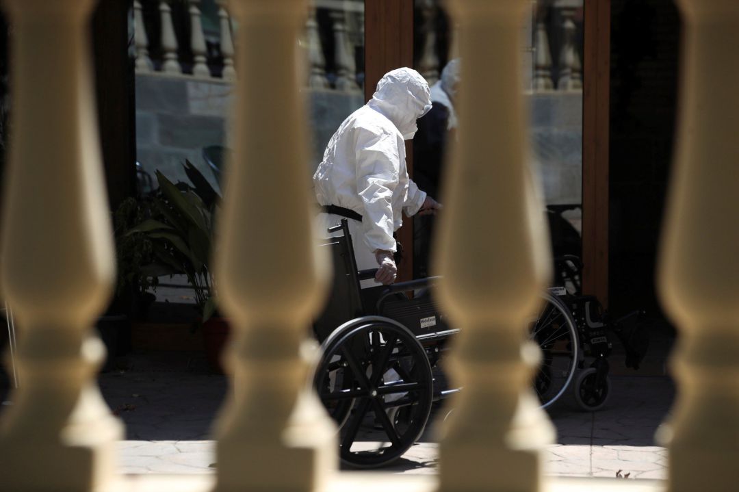 Un trabajador introduce una silla de ruedas en una residencia de Mayores Un trabajador introduce una silla de ruedas en una residencia de Mayores