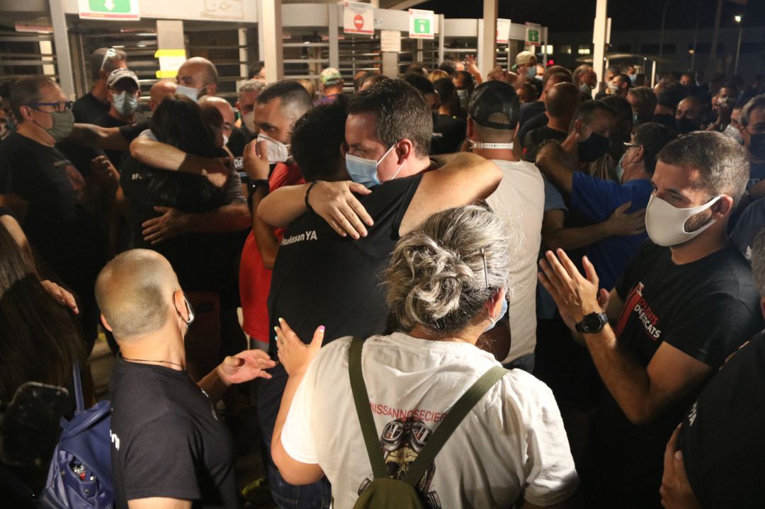 Dos treballadors de Nissan abraçant-se a la Zona Franca després de que els sindicats i l'empresa hagin arribat a un acord Dos treballadors de Nissan abraçant-se a la Zona Franca després de que els sindicats i l'empresa hagin arribat a un acord