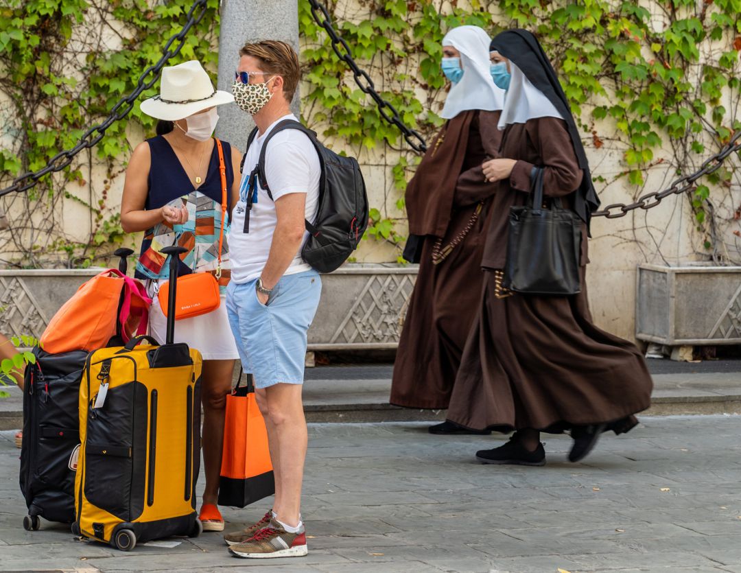 Unos turistas esperan el autobús mientras una pareja de monjas de la Orden de Santa Ángela de la Cruz pasan por detrás con mascarillas. Unos turistas esperan el autobús mientras una pareja de monjas de la Orden de Santa Ángela de la Cruz pasan por detrás con mascarillas.