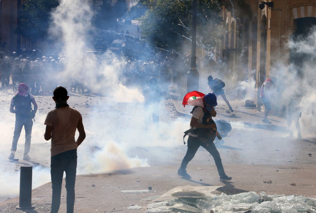 Los manifestantes participan en una protesta en medio de una nube de gas lacrimógeno disparado por la policía, tras la explosión del martes, en Beirut Los manifestantes participan en una protesta en medio de una nube de gas lacrimógeno disparado por la policía, tras la explosión del martes, en Beirut