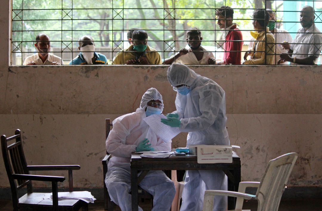 Los trabajadores sanitarios que usan trajes de protección comprueban la información del paciente escrita en un papel antes de realizar una prueba rápida de antígenos en la India Los trabajadores sanitarios que usan trajes de protección comprueban la información del paciente escrita en un papel antes de realizar una prueba rápida de antígenos en la India