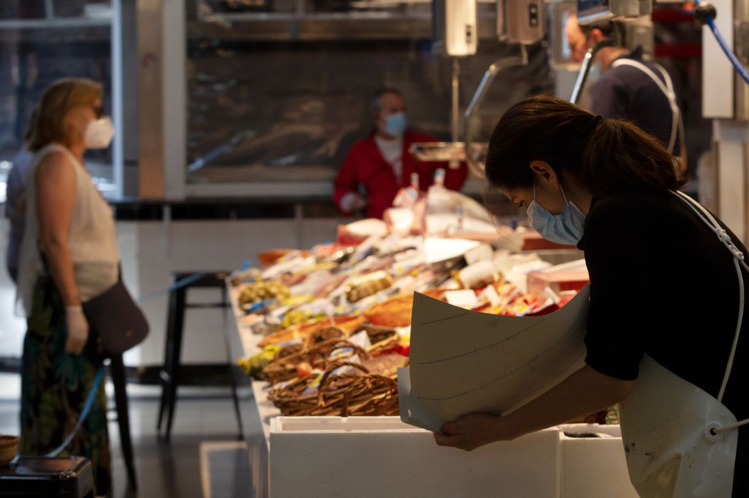 Una mujer compra en una pescadería de un mercado de España Una mujer compra en una pescadería de un mercado de España