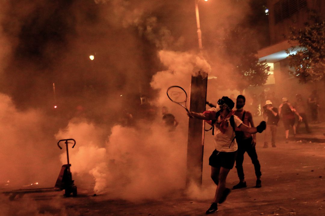 Un activista antigubernamental utiliza una raqueta de tenis para lanzar bombas lacrimógenas a la policía antidisturbios durante enfrentamientos cerca de la casa del Parlamento libanés Un activista antigubernamental utiliza una raqueta de tenis para lanzar bombas lacrimógenas a la policía antidisturbios durante enfrentamientos cerca de la casa del Parlamento libanés