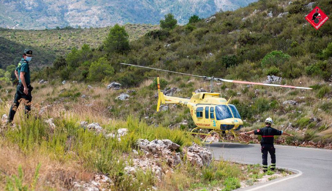 Un instante del fuego de la Vall de Gallinera con un helicóptero aterrizando en la carretera Un instante del fuego de la Vall de Gallinera con un helicóptero aterrizando en la carretera