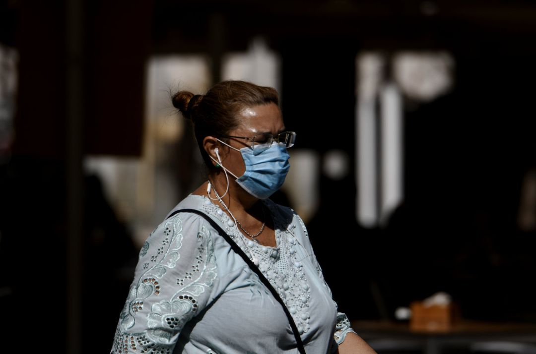 Una mujer camina con mascarilla. Una mujer camina con mascarilla.
