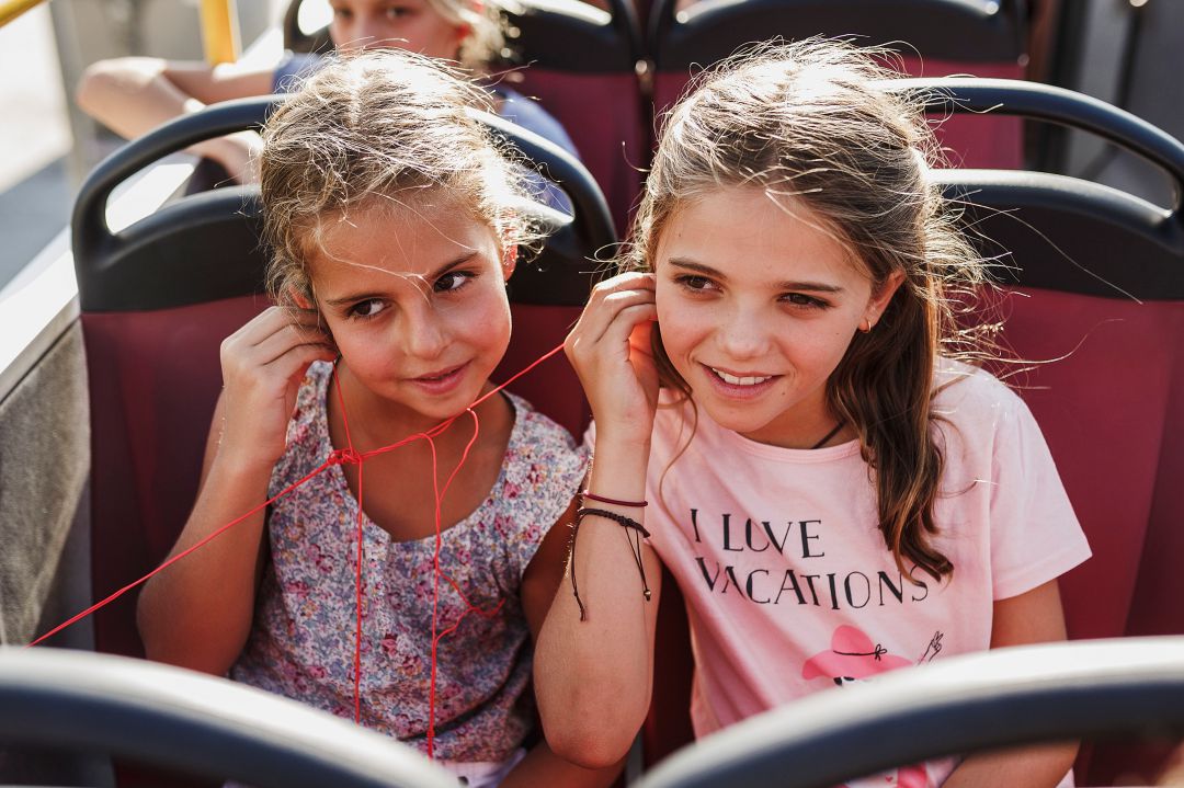 Dos pequeñas disfrutan de su viaje en un bus turístico de City Shightheen Dos pequeñas disfrutan de su viaje en un bus turístico de City Shightheen