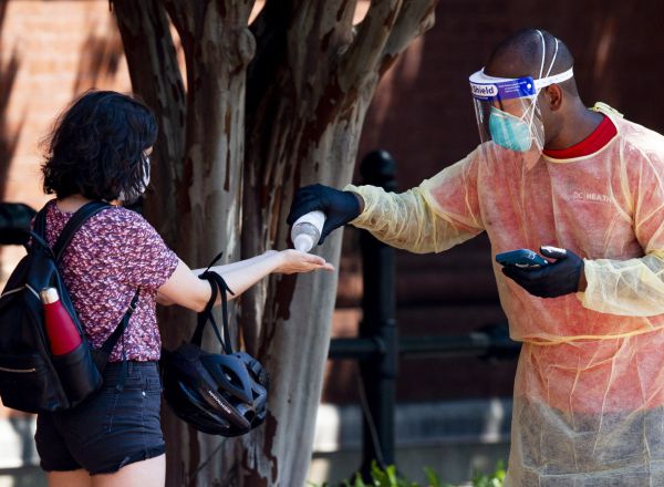 Un miembro del equipo sanitario estadounidense ofrece gel hidroalcohólico a una joven en Washington