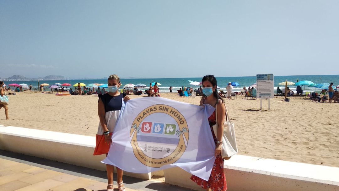 Mari Carmen Sánchez (d) y una técnico de la concejalía, con la bandera de playa sin humo de Urbanova Mari Carmen Sánchez (d) y una técnico de la concejalía, con la bandera de playa sin humo de Urbanova