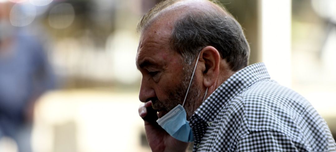 Un hombre con mascarilla habla por teléfono. Un hombre con mascarilla habla por teléfono.