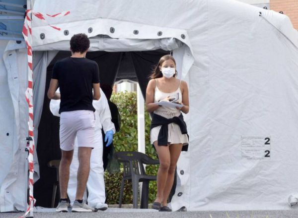 Una chica sale de área portatil ubicada frante a un hospital tras realizarle el personal sanitario una PCR.