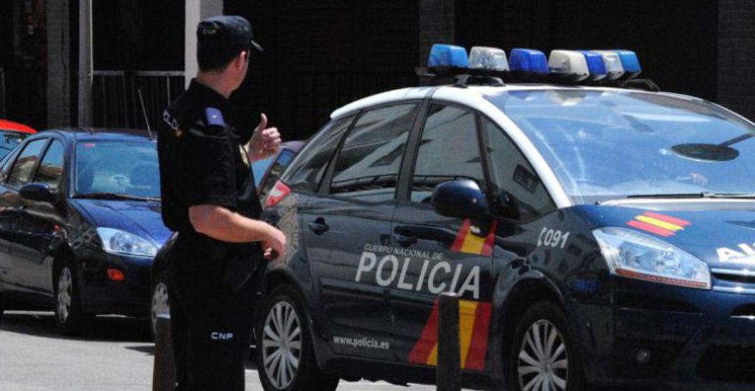 Un Policía Nacional frente a uno de los vehículos del cuerpo Un Policía Nacional frente a uno de los vehículos del cuerpo