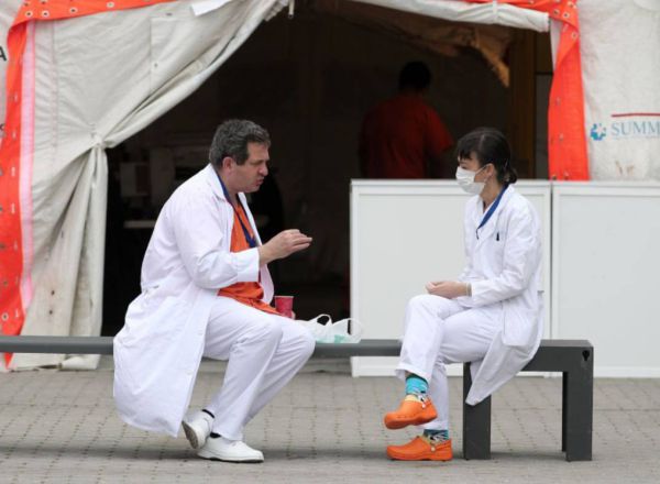 Dos sanitarios conversan sobre un banco
