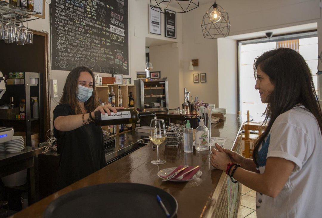 Una camarera sirve una copa de vino a una clienta Una camarera sirve una copa de vino a una clienta