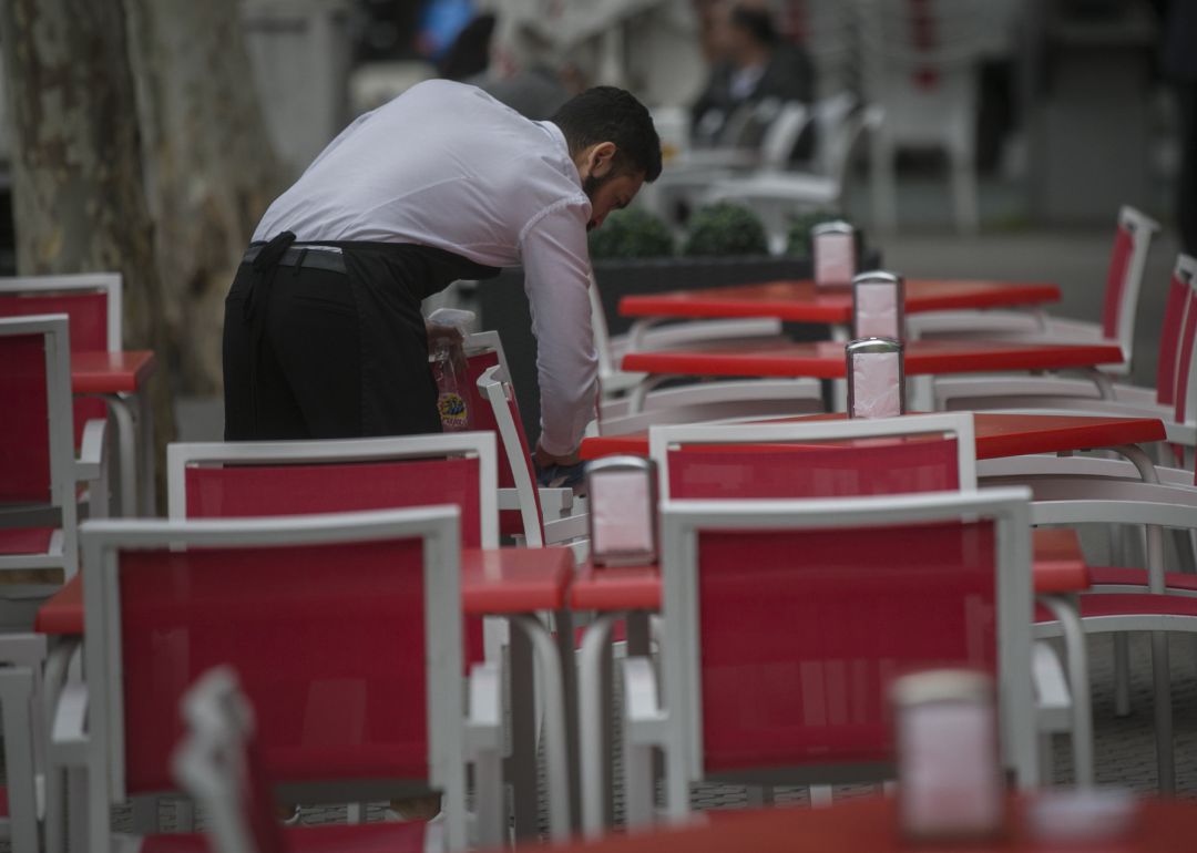 Un camarero limpia las mesas de una terraza. Un camarero limpia las mesas de una terraza.