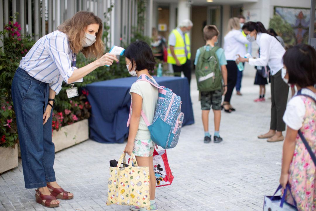 Una trabajadora toma la temperatura a una niña a la entrada de un colegio Una trabajadora toma la temperatura a una niña a la entrada de un colegio