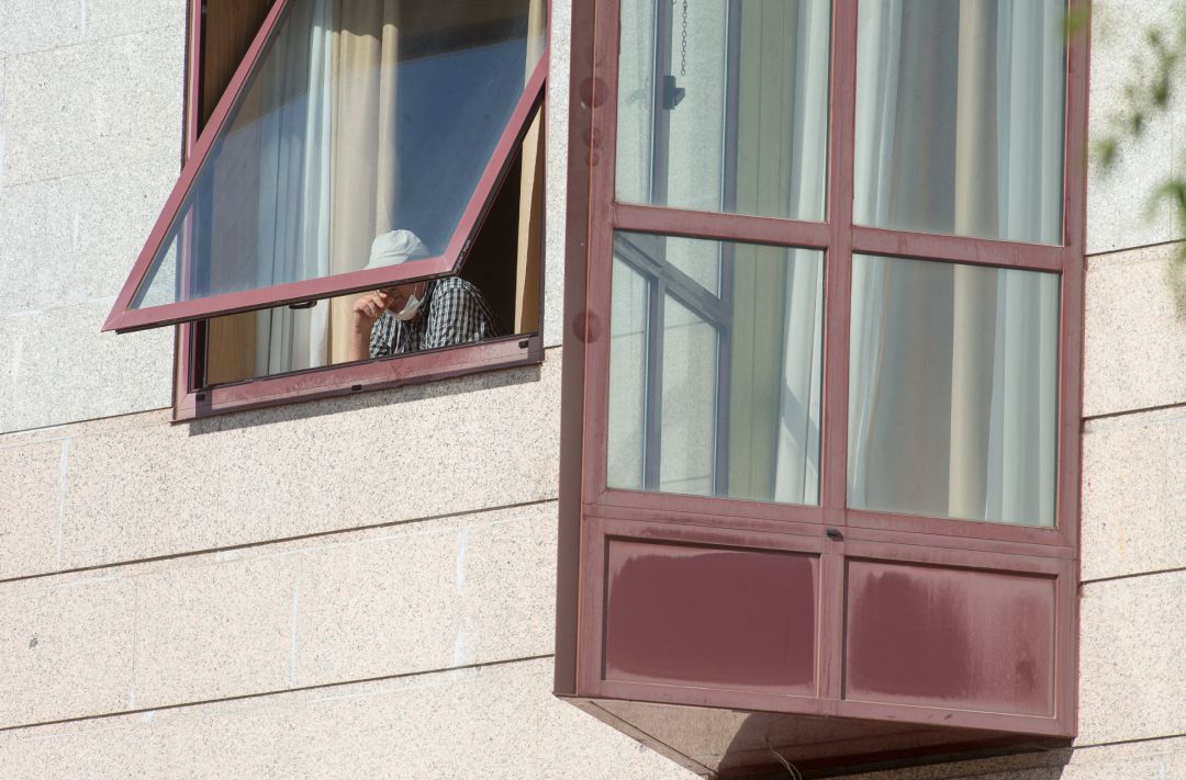 Una persona se asoma por la ventana de una residencia de mayores Una persona se asoma por la ventana de una residencia de mayores