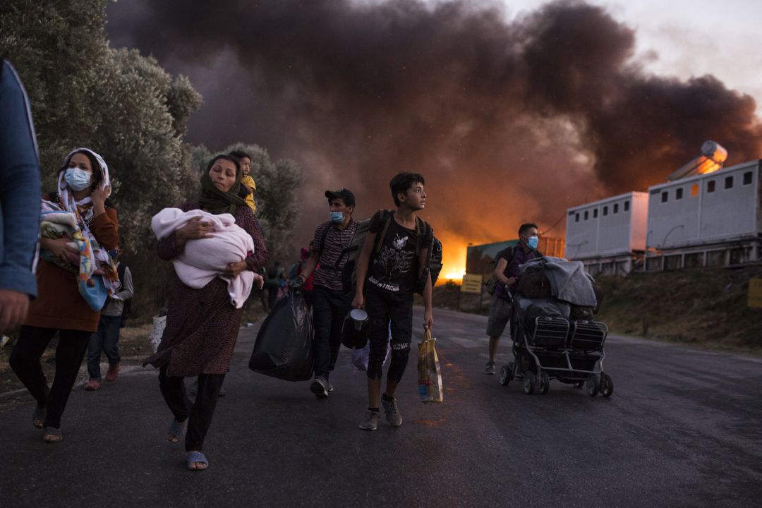 Refugiados con sus pertenencias huyen de Moria tras el incendio en el campamento Refugiados con sus pertenencias huyen de Moria tras el incendio en el campamento