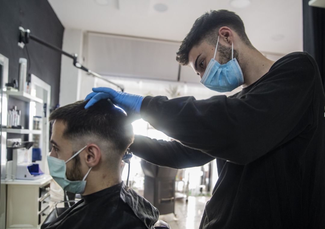 Un peluquero atiende a un cliente en su peluquería Un peluquero atiende a un cliente en su peluquería