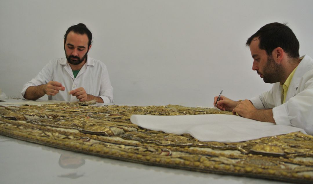 Dos técnicos del estudio CYRTA trabajan sobre la denominada saya de "los corbatines" Dos técnicos del estudio CYRTA trabajan sobre la denominada saya de "los corbatines"