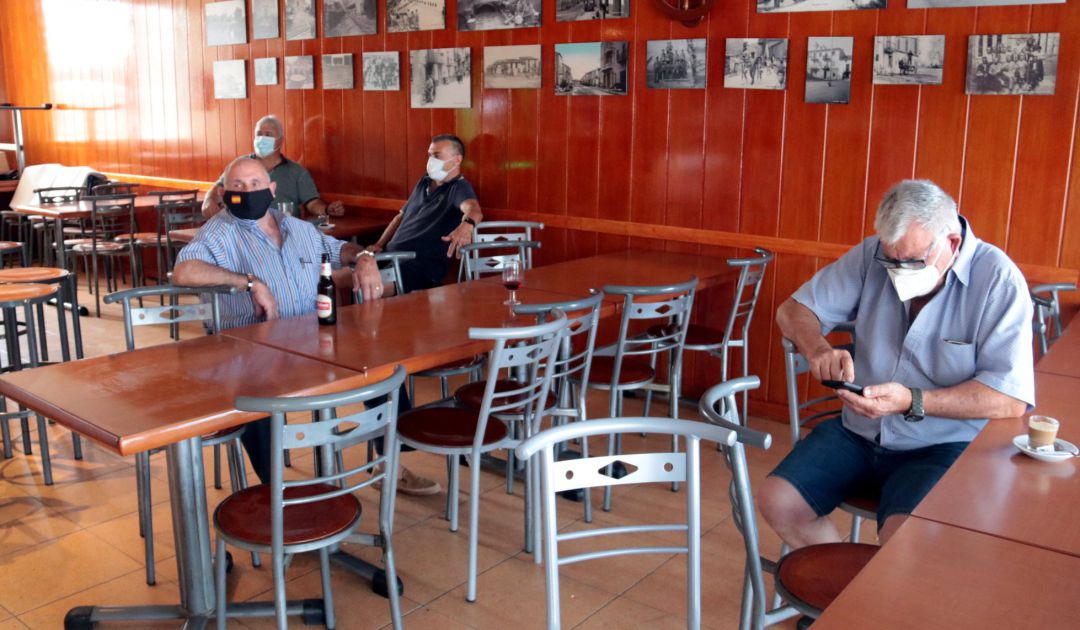 Varios hombres con mascarillas en el interior de un bar. Varios hombres con mascarillas en el interior de un bar.