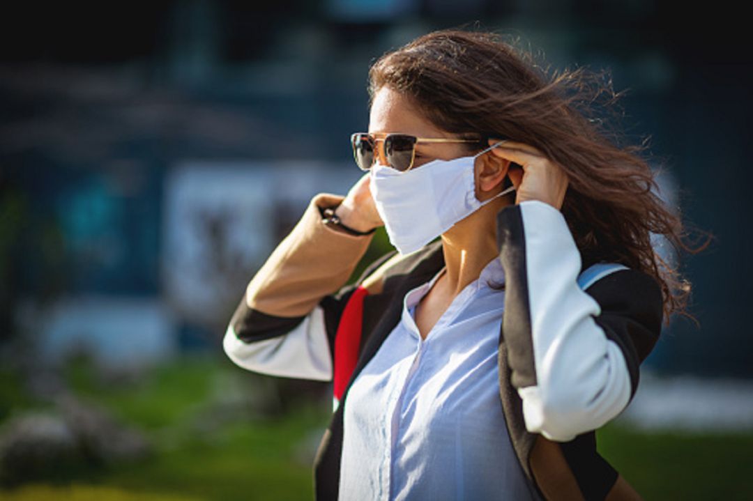 Mujer poniéndose la mascarilla en la calle Mujer poniéndose la mascarilla en la calle