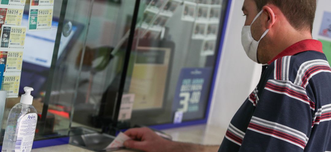Un hombre compra lotería en una administración Un hombre compra lotería en una administración