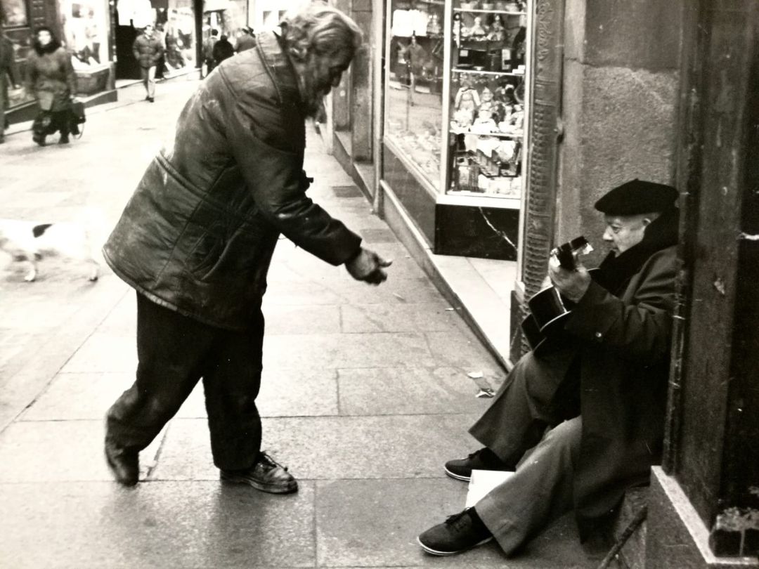 Patricio echa una moneda a Basilio en la Calle Real Patricio echa una moneda a Basilio en la Calle Real
