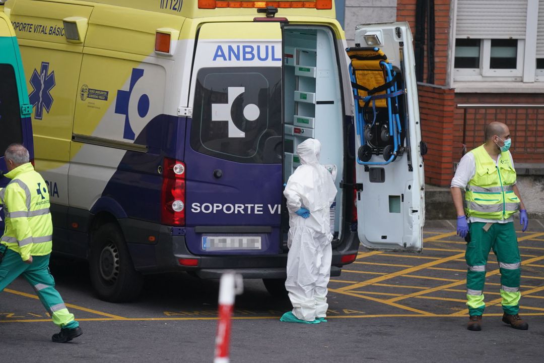 Varios sanitarios protegidos, junto a una ambulancia Varios sanitarios protegidos, junto a una ambulancia