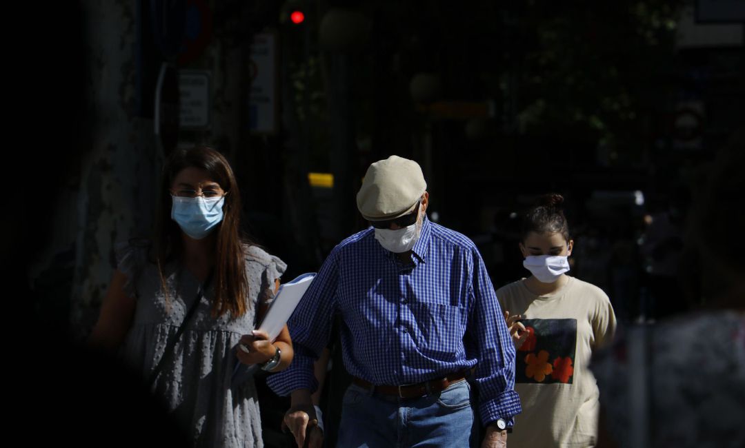 Personas con mascarilla caminan por una calle Personas con mascarilla caminan por una calle